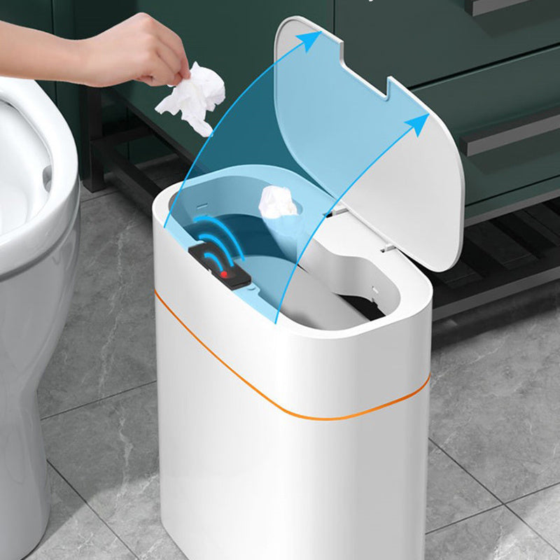 Touchless smart trash can in a bathroom with a user disposing of waste, showcasing its automatic lid feature.