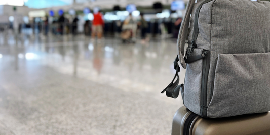 Gray backpack and suitcase at busy airport terminal representing travel essentials collection