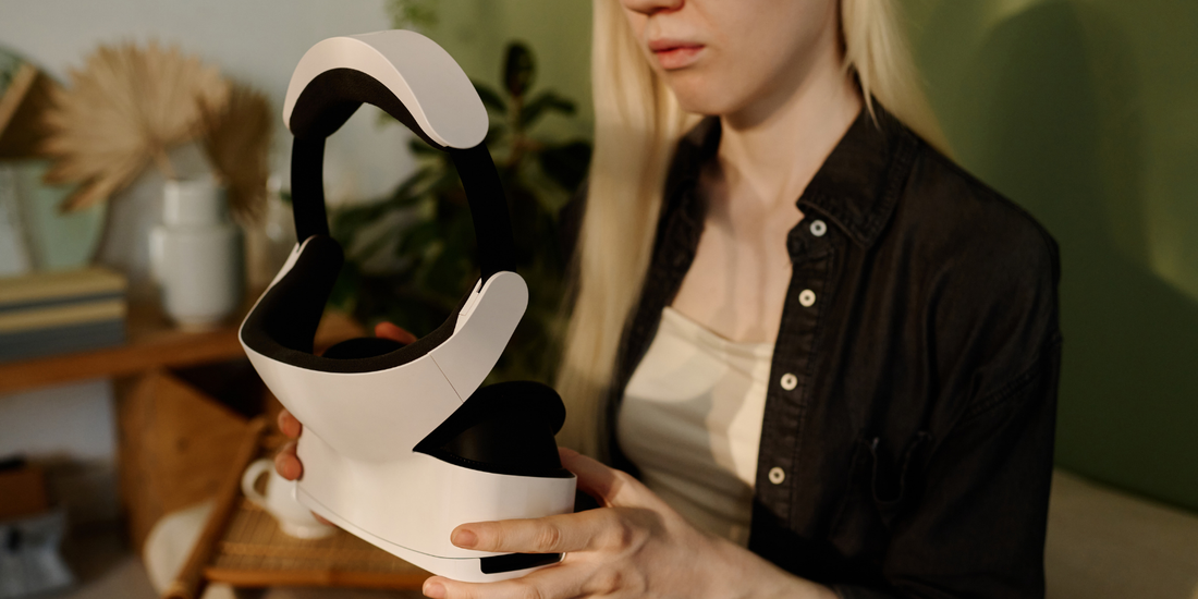 woman holding white and black neck and head massager health and wellness gadget in cozy home setting