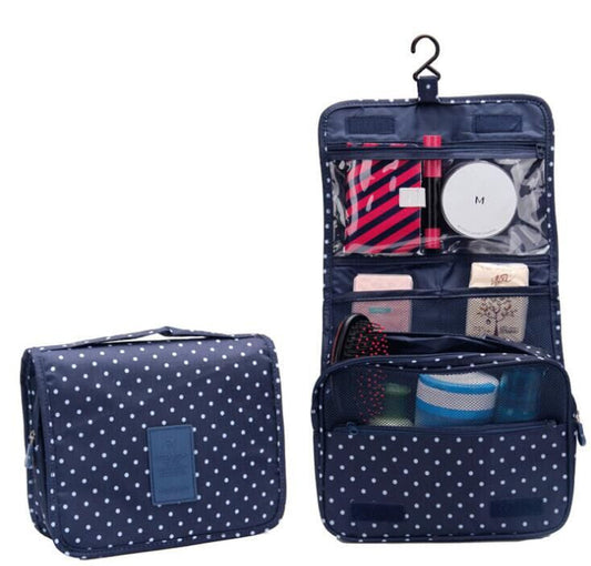 Navy blue hanging foldable toiletry bag with white polka dots, multiple compartments, and built-in hook, shown closed and open with organized grooming essentials.